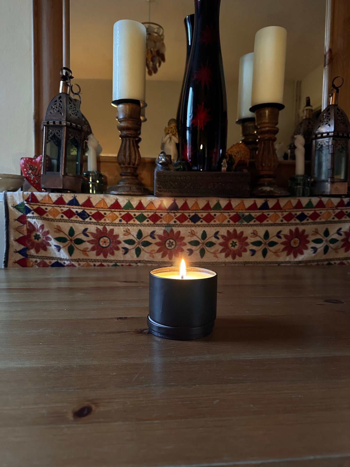 a hand poured candle that is alight in someone's dining room with a mirror in the background