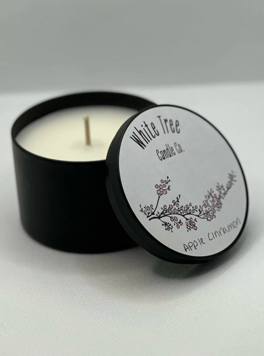 a hand poured candle that smell like cinnamon and apple in a black tin, a Christmas candle